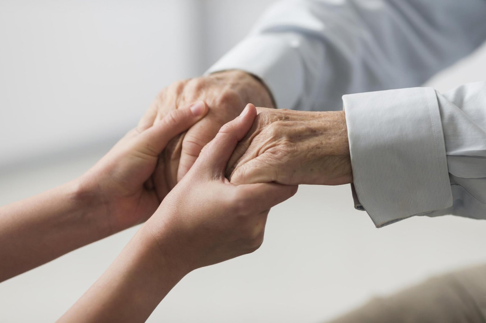 Mãos jovens segurando as mãos de uma pessoa idosa